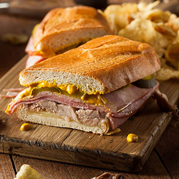 Cuban-Sandwich Cuban sandwich on a cutting board with chips